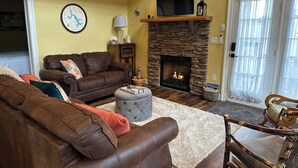 A cozy living room with a stone fireplace, leather sofas, and a television. - New: Charming and Cozy, Great Value! (Swanton)