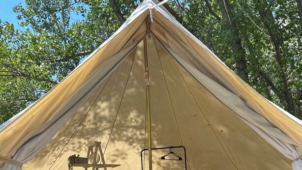 A tent with a bed, a chair, a ladder, and a hanging light fixture. - #Y3 Willow Tree - 1 Queen bed - No Pets Please (Drumheller)