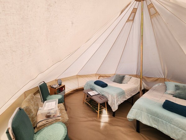 A cozy tent with two beds, a small table, and a chair.