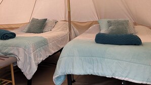 Una carpa con dos camas, cada una con una almohada y una manta.