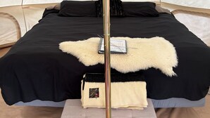 Una tienda de campaña con una cama, una lámpara y una pequeña mesa con un libro.
