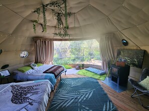 Ein gemütliches Zeltzimmer mit Bett, Fernseher und Blick ins Freie.