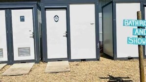 A row of portable restrooms with a sign indicating "BATHROOM AND SHOWERS". - #D3 Rainforest Getaway Dome- 2 Dbl beds-No pets Please (Drumheller)