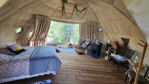 A cozy tent with a bed, a small table, and a chair. - #D4 Badlands Bunker Dome-1 Queen bed -Pet friendly (Drumheller)