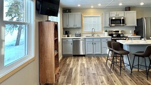 A modern kitchen with wooden flooring, a built-in oven, microwave, and sink. - Charming 3-bedroom cabin right on the sandy shore of beautiful Star Lake. (Dent)