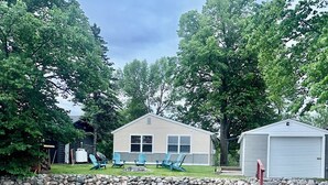 A lakeside cabin with a dock, surrounded by trees and a stone wall. - Charming 3-bedroom cabin right on the sandy shore of beautiful Star Lake. (Dent)