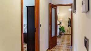 A hallway with a wooden door, a mirror, a lamp, and a potted plant. - Open Horizon - Short Rent (Zafferana Etnea)