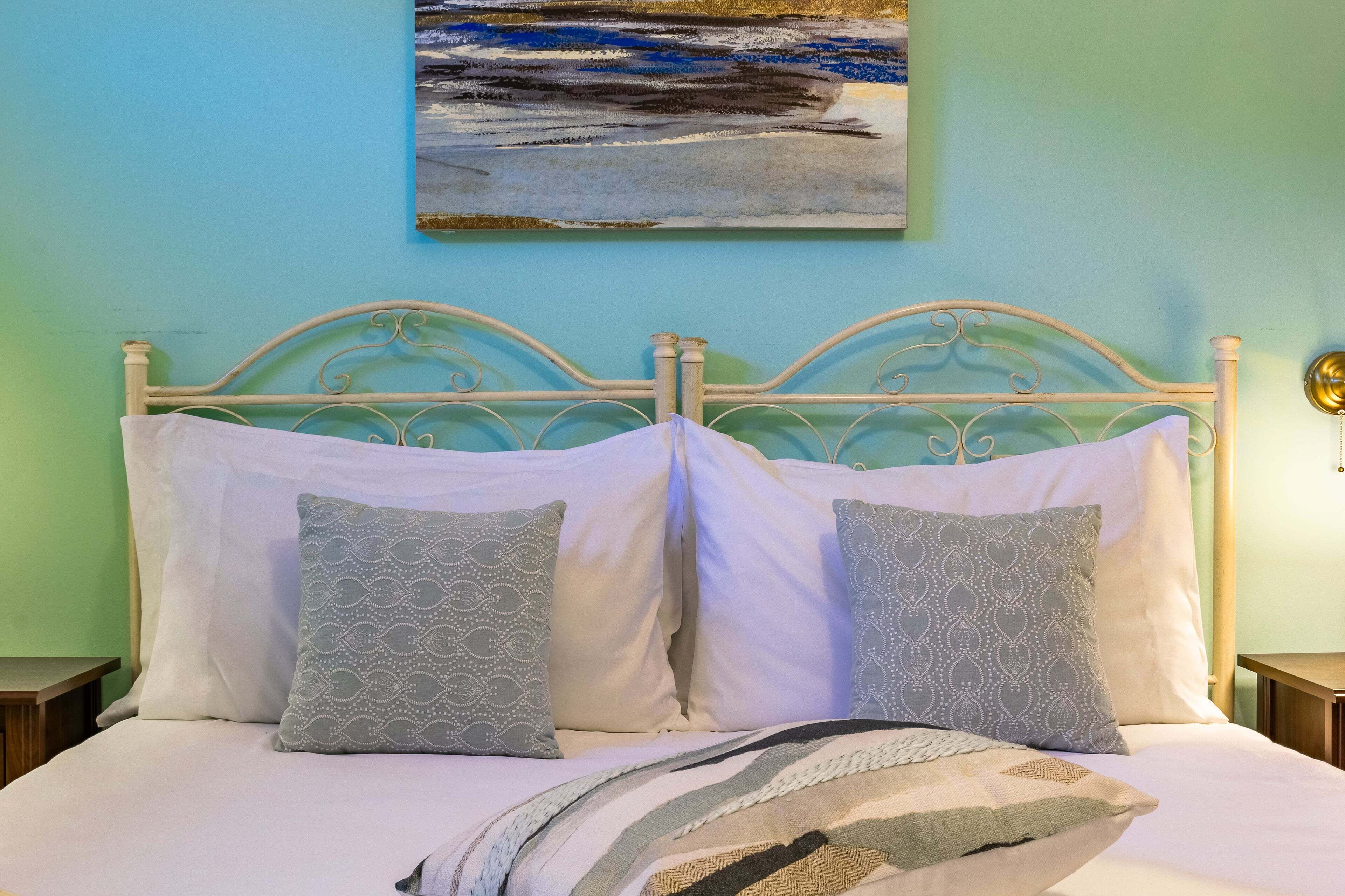 Un letto con una testiera bianca, due cuscini decorati e una coperta.