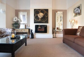 Una sala de estar con chimenea, un sofá, una mesa de centro y objetos decorativos.