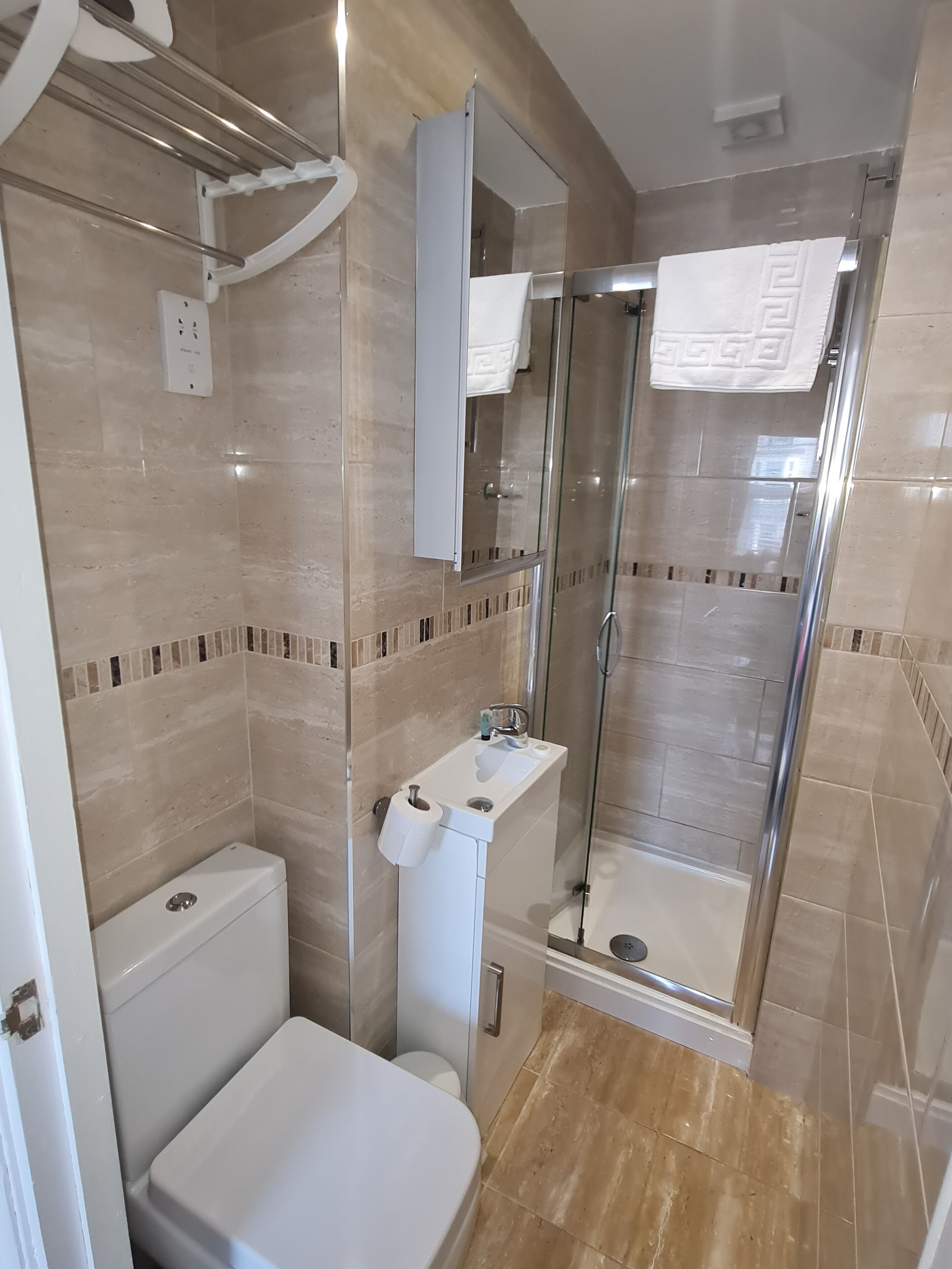 A bathroom with a toilet, sink, and glass shower enclosure.