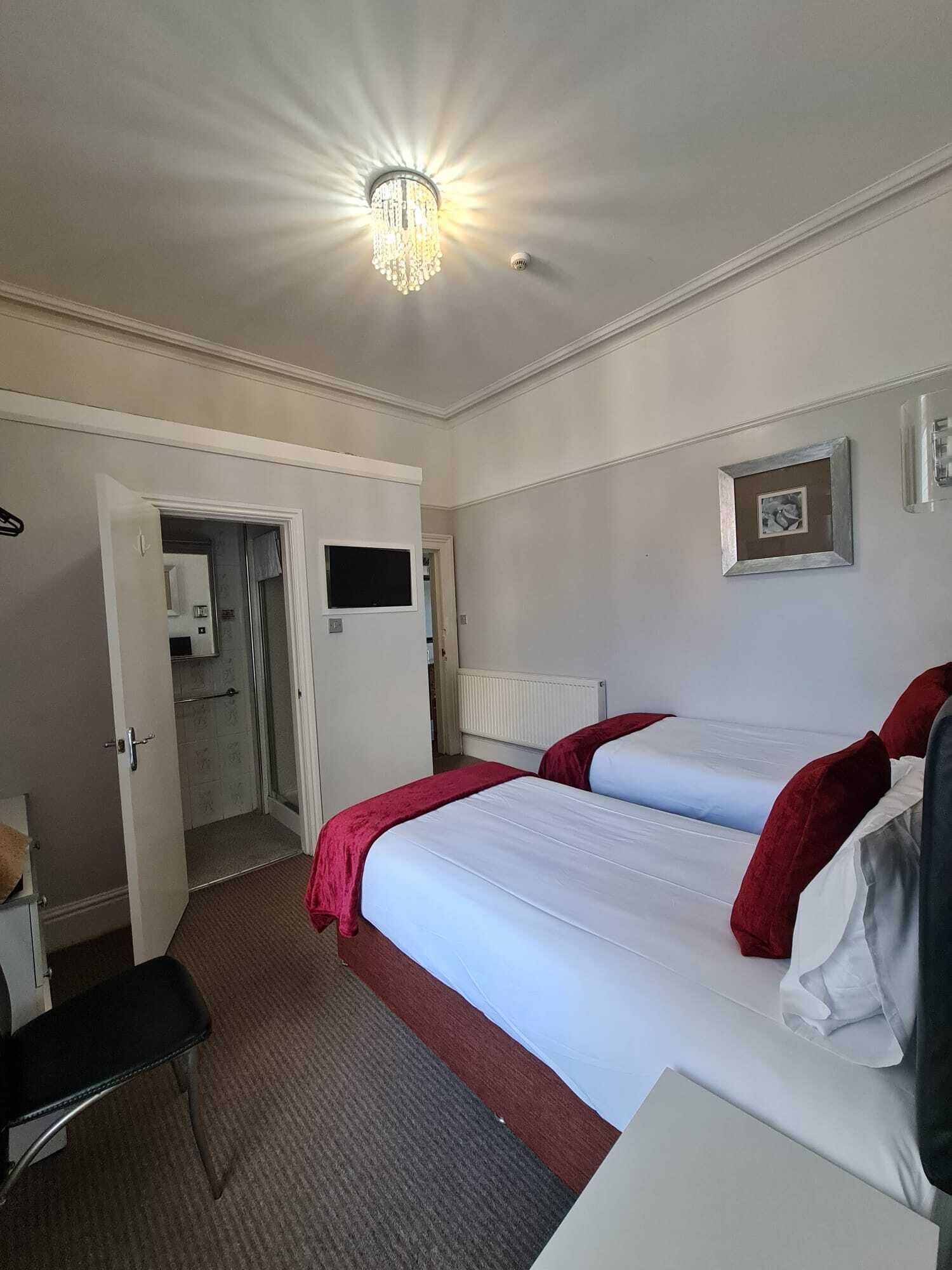 A hotel room with a bed, a desk, a chair, a wardrobe, and a bathroom.