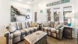 A living room with two sofas, a coffee table, and a painting on the wall. - Special Shell features 2BD/2BA w/private, fenced yard, swim spa, outdoor fireplace! (Port St. Joe)