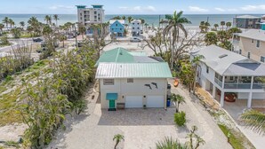 A coastal residential area with houses, palm trees, and a beach in the background.