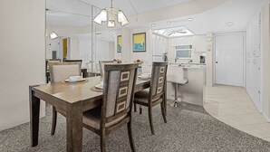 Ein Essbereich mit Holztisch und -stühlen, einer Chandelierleuchtre und einer Küche im Hintergrund.