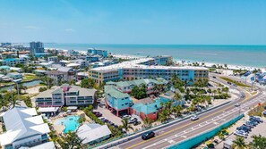 A coastal hotel with multiple buildings, a swimming pool, and a beach view. - Private Balcony & Community Pool - TLC Beach Escapes - Roelens (Fort Myers Beach)