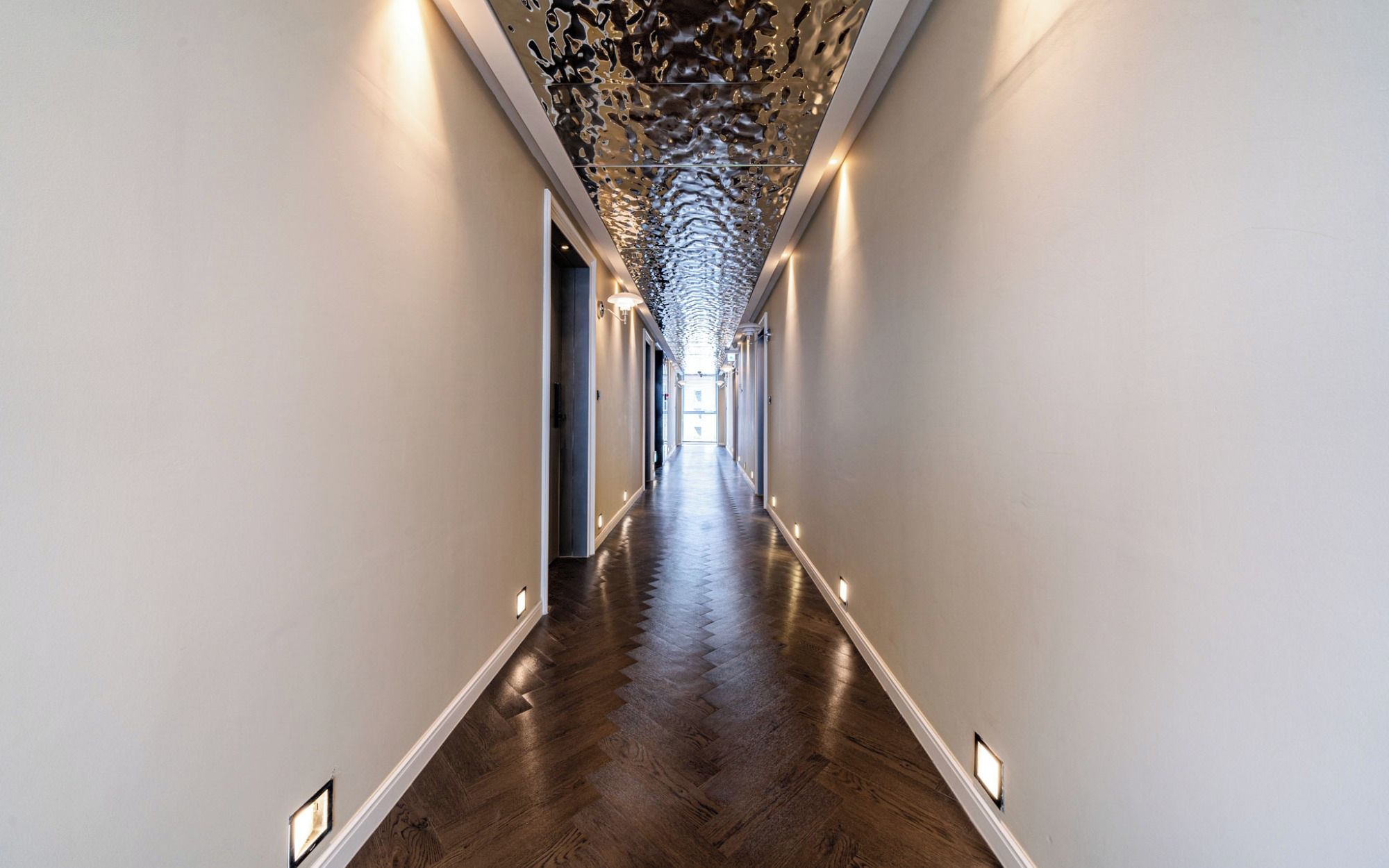 A long, narrow hallway with a wooden floor and white walls.