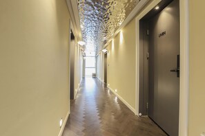 A hallway with a patterned ceiling, a door labeled "LINEN," and a wooden floor. - Brown-dot Hotel Haeundae (Busan)