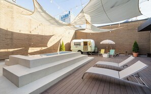 A rooftop patio with a pool, lounge chairs, a caravan, and a brick wall. - Brown-dot Hotel Haeundae (Busan)