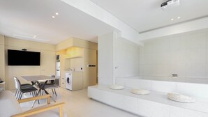 A modern kitchen with a dining area, a flat-screen TV, and a built-in oven. - Brown-dot Hotel Haeundae (Busan)