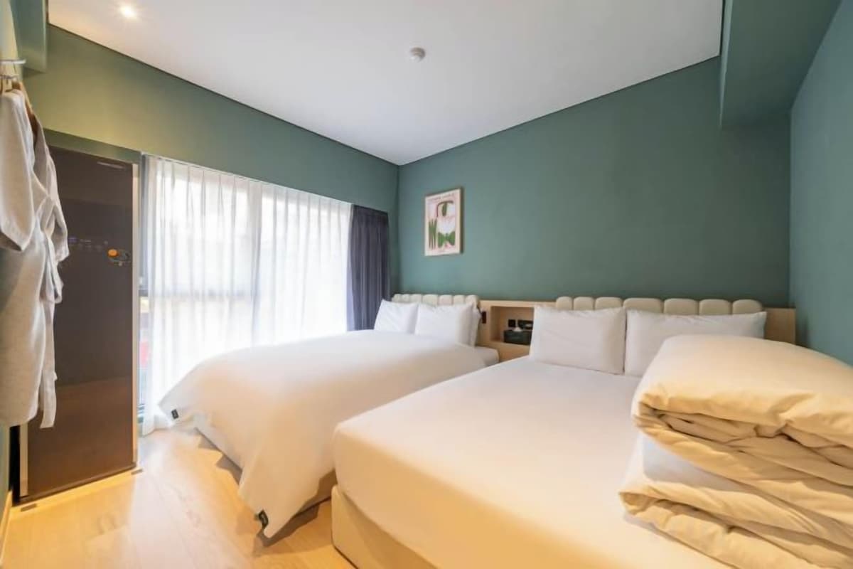 A hotel room with two beds, a wardrobe, and a window with curtains.