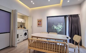 A modern kitchen with a built-in washing machine, a dining area with a round table and chairs, and a large window with curtains. - Brown-dot Hotel Haeundae (Busan)