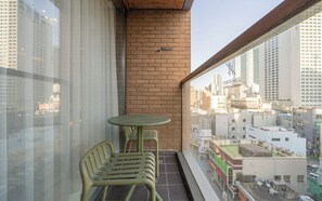 A balcony with a table and two chairs, a brick wall, and a view of a cityscape. - Brown-dot Hotel Haeundae (Busan)