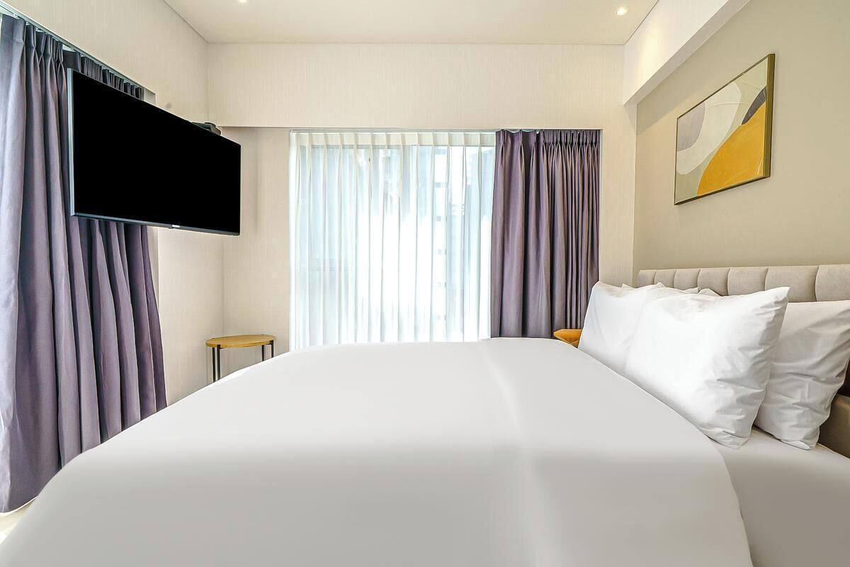Ein Hotelzimmer mit einem Bett, einem an der Wand befestigten Flachbildfernseher, einem kleinen runden Tisch und einem Bild an der Wand.