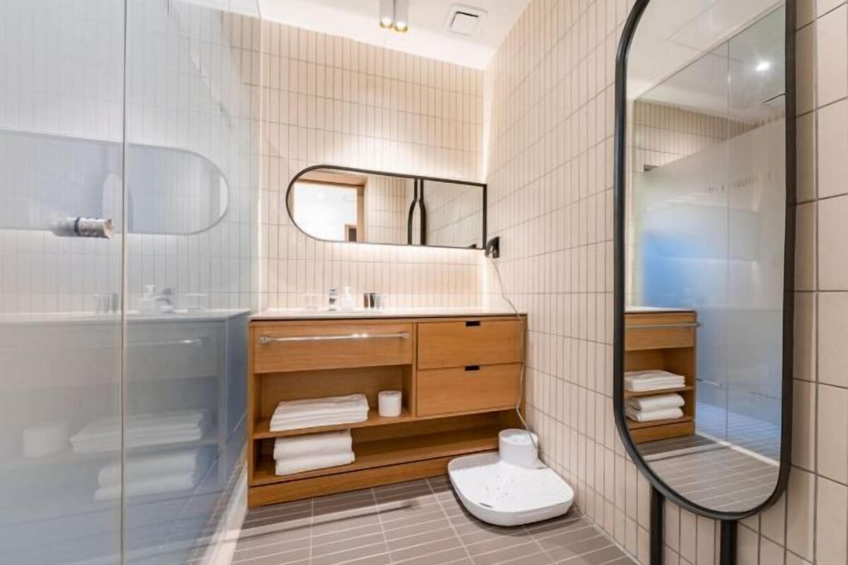 A modern bathroom with a glass shower enclosure, a wooden vanity with a mirror, and a white toilet.