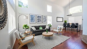 Una sala de estar moderna con un sofá, dos sillones, una mesa de centro redonda y un comedor con mesa y sillas.