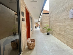 A corridor with a tiled floor, a wicker basket, and potted plants. - Hotel 28 (Cancun)
