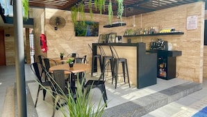 An outdoor patio with a pool, a wooden pergola, hanging plants, a bar area, and a seating arrangement. - Hotel 28 (Cancun)