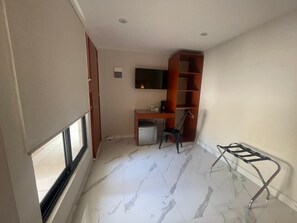 A room with a desk, chair, TV, and a metal rack. - Hotel 28 (Cancun)