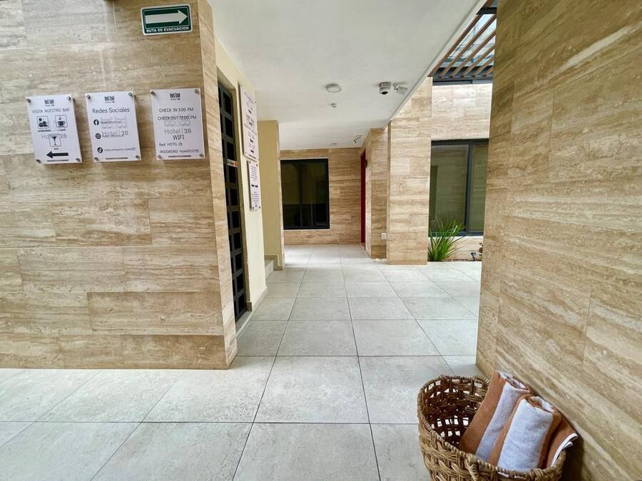 A hotel corridor with tiled flooring, a reception desk, and informational signs.