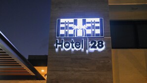 A hotel sign with palm trees and the number 28. - Hotel 28 (Cancun)