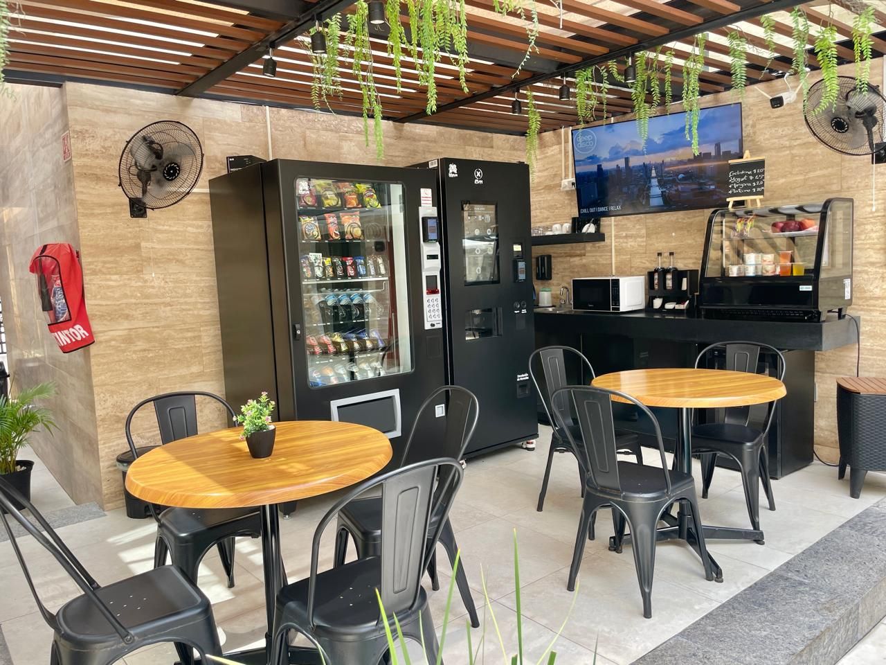 Una zona de estar con mesas y sillas, una máquina expendedora y una estación de café.