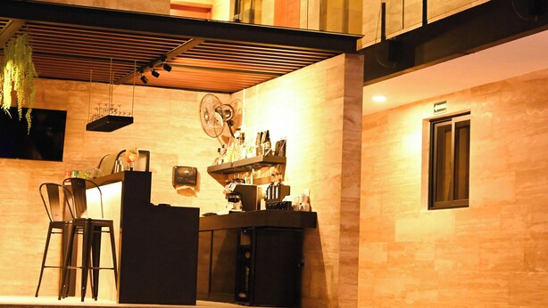 A modern multi-story building with a pool area, outdoor seating, and a bar. - Hotel 28 (Cancun)