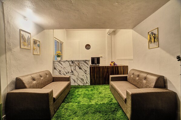 A room with two sofas, a marble wall, and a green carpet.
