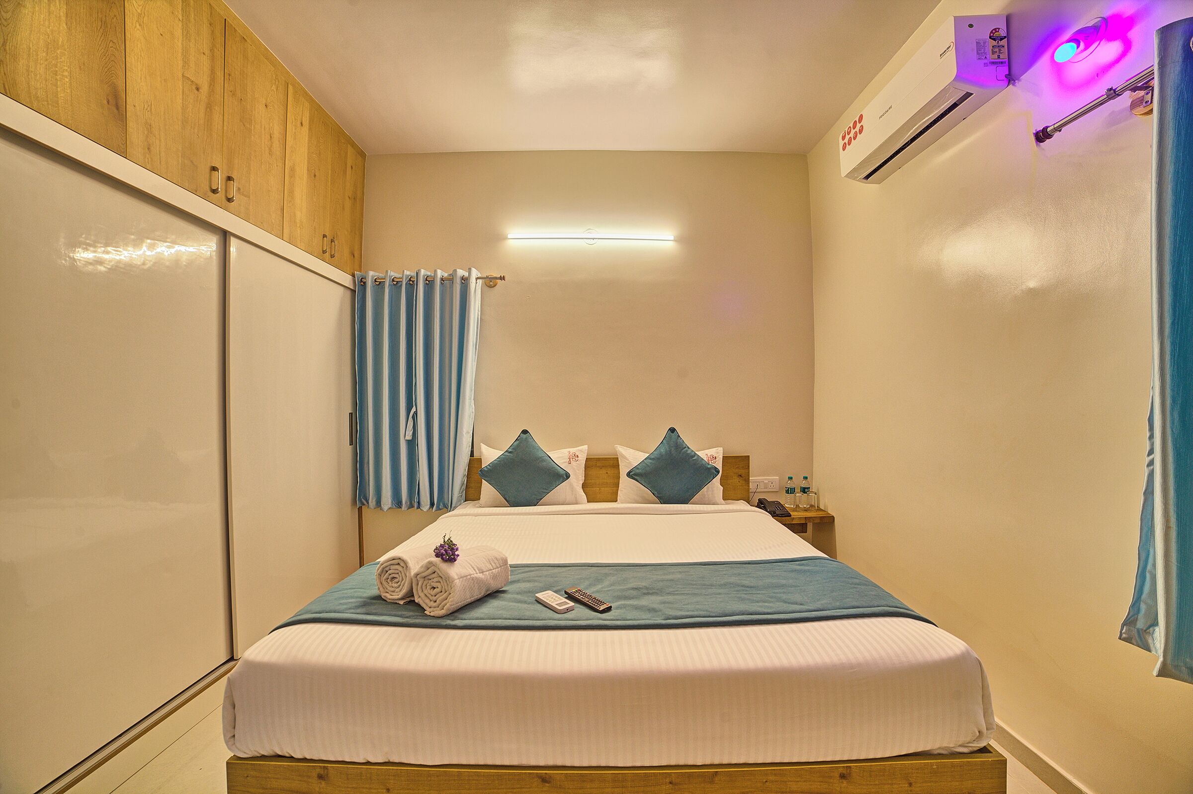 Une chambre d’hôtel comprenant un lit, une table de chevet, un miroir et une armoire.