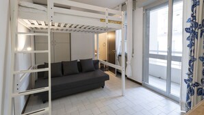 A room with a bunk bed, a sofa, a sliding glass door, and a view of the outside. - GuestHost - Comfortable 28 sqm studio apartment, ideal for 2 people, located on the first floor of a renovated building with elevator (3 stairs to access it). The accommodation is located in a quiet residential area, about 50 meters from the beach.A 2-mi (Rimini)