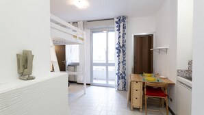 A room with a bunk bed, a dining table with chairs, a kitchen area, and a sliding glass door leading to an outdoor balcony. - GuestHost - Comfortable 28 sqm studio apartment, ideal for 2 people, located on the first floor of a renovated building with elevator (3 stairs to access it). The accommodation is located in a quiet residential area, about 50 meters from the beach.A 2-mi (Rimini)