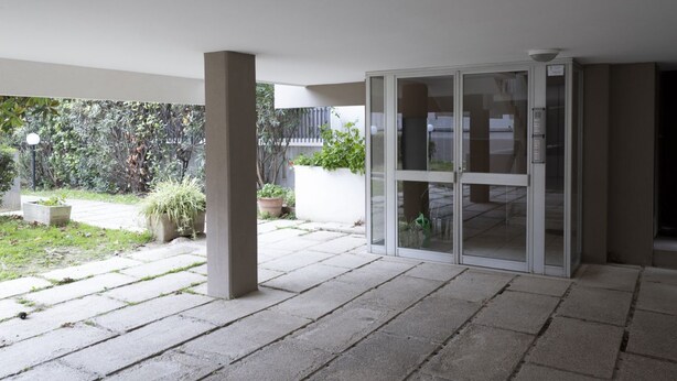 A modern building with a glass door entrance, a concrete patio, and a view of a garden. - GuestHost - Comfortable 28 sqm studio apartment, ideal for 2 people, located on the first floor of a renovated building with elevator (3 stairs to access it). The accommodation is located in a quiet residential area, about 50 meters from the beach.A 2-mi (Rimini)