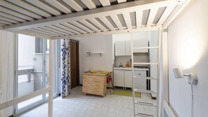 A room with a wooden table, a kitchen area with cabinets, a white door, and a ceiling with wooden beams. - GuestHost - Comfortable 28 sqm studio apartment, ideal for 2 people, located on the first floor of a renovated building with elevator (3 stairs to access it). The accommodation is located in a quiet residential area, about 50 meters from the beach.A 2-mi (Rimini)