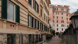 A narrow cobblestone street flanked by multi-story buildings with balconies and shutters. - GuestHost - Trastevere Station Bright Apartment with Terrace (Roma)