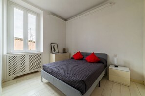 A bedroom with a bed, a nightstand, a window, and a radiator. - GuestHost - Trastevere Station Bright Apartment with Terrace (Roma)