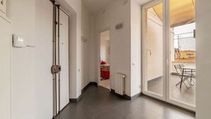 A hallway with a sliding glass door leading to an outdoor area with a table and chairs. - GuestHost - Trastevere Station Bright Apartment with Terrace (Roma)