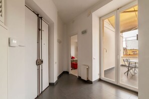Un couloir avec une porte-fenêtre coulissante donnant sur un espace extérieur aménagé avec une table et des chaises.