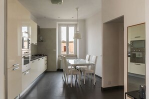 A modern kitchen with white cabinets, a dining table with chairs, and a window with a view.
