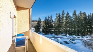 Ein Balkon mit Blick auf einen verschneiten Parkplatz und Bäume.