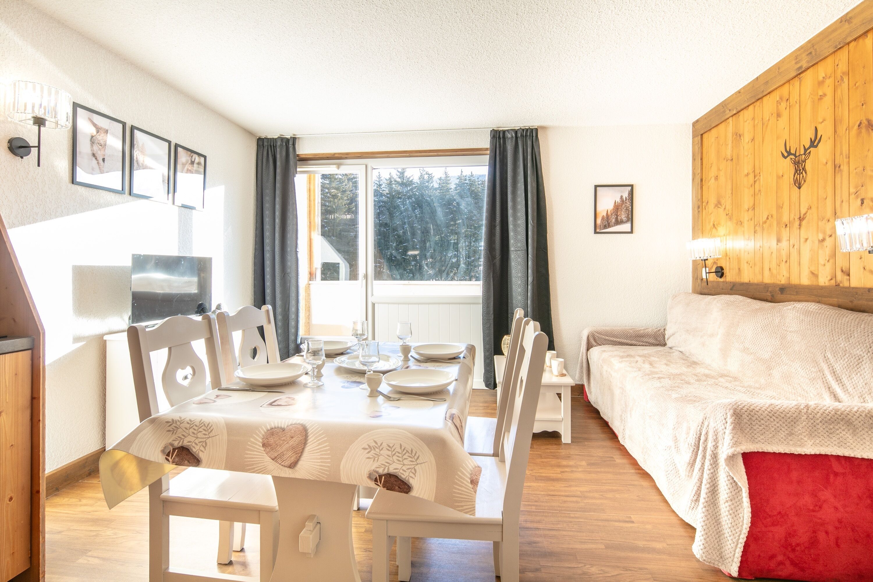 A cozy room with a dining table set for four, a sofa, and a wooden headboard.