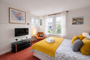 A hotel room with a bed, a TV, a chair, and a window with curtains. - The Victorian Fulham Retreat. 2BR Spacious (London)